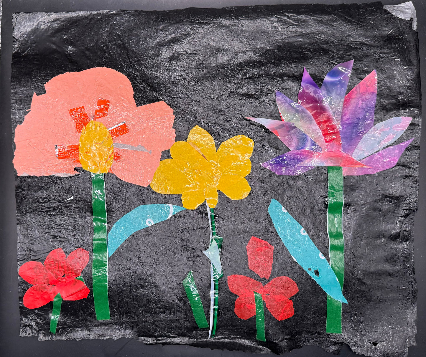 Colorful plastic flowers on a textured black background