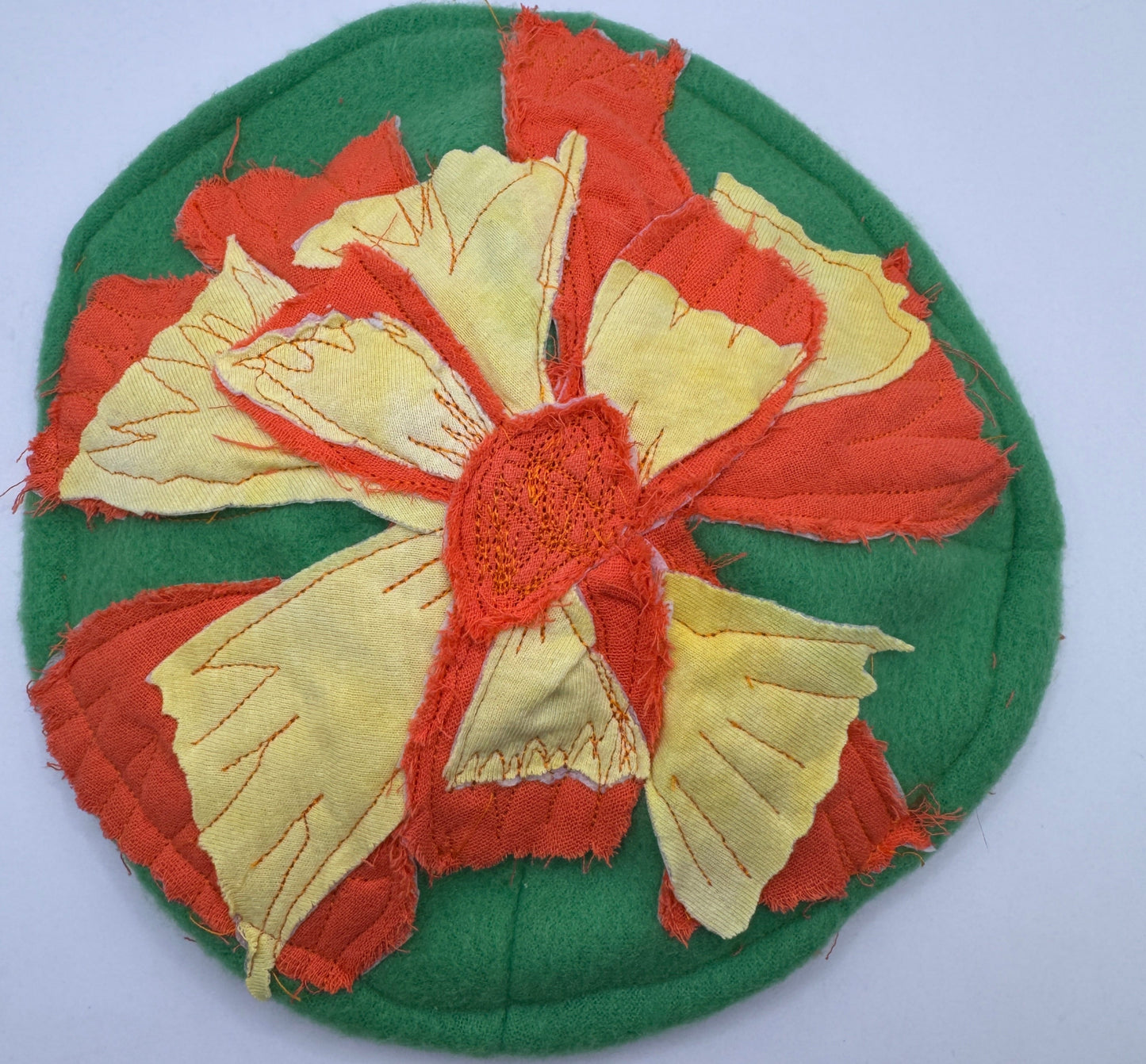 Decorative patch with red and yellow flower design on a green background